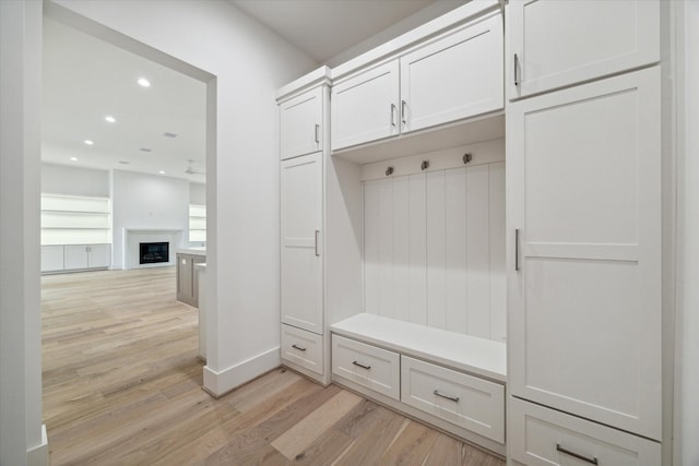 mudroom with baseboards, light wood-type flooring, a fireplace, and recessed lighting