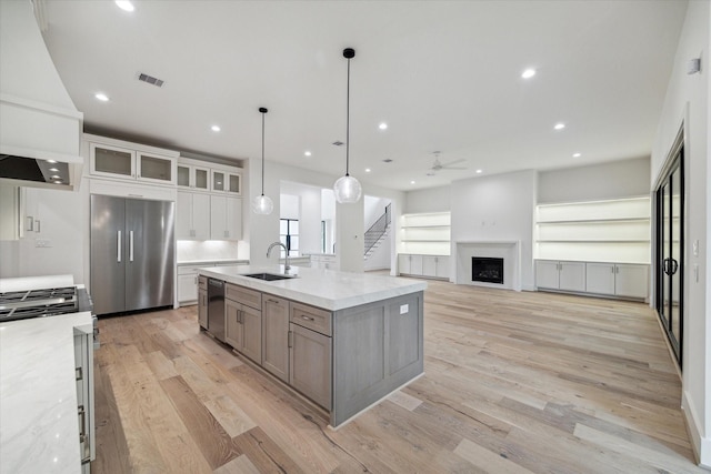 kitchen with light wood-type flooring, a fireplace, appliances with stainless steel finishes, and a sink