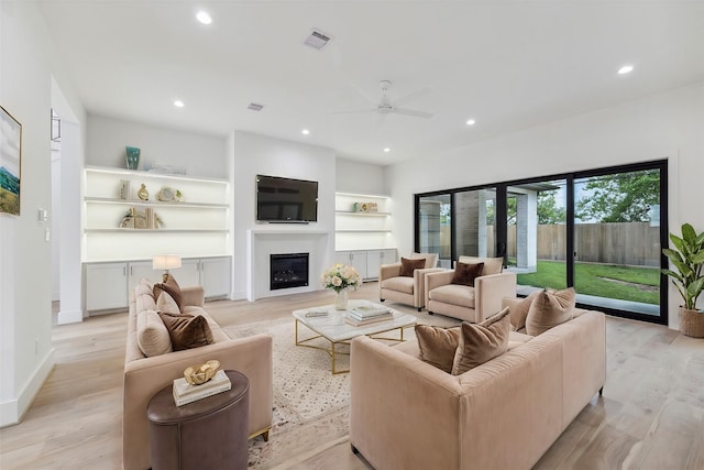 living room with a glass covered fireplace, light wood-style flooring, and recessed lighting