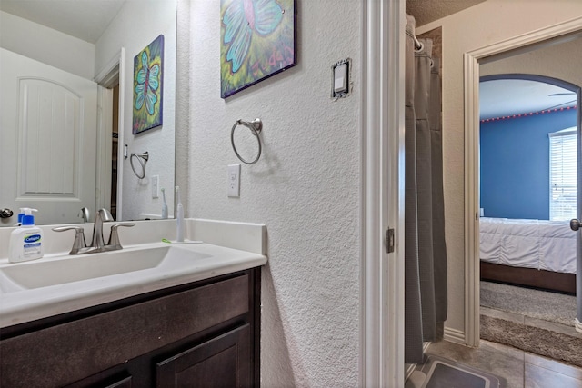 ensuite bathroom featuring a textured wall, a shower with shower curtain, ensuite bathroom, vanity, and tile patterned floors