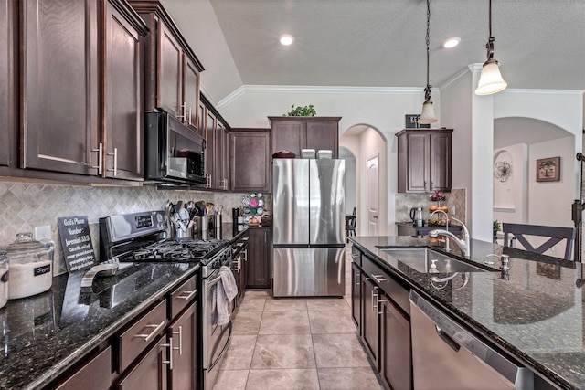 kitchen featuring appliances with stainless steel finishes, arched walkways, a sink, and dark stone countertops