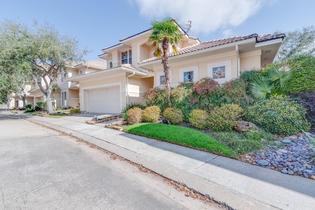 mediterranean / spanish home featuring a garage, concrete driveway, a tiled roof, and stucco siding