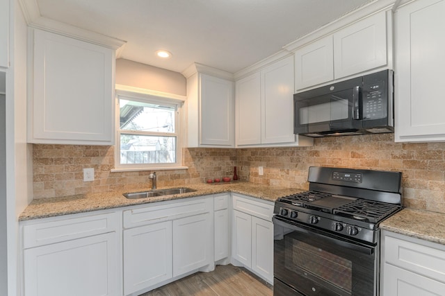 kitchen with black appliances, light stone counters, white cabinets, and a sink