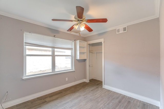 unfurnished bedroom featuring light wood finished floors, baseboards, visible vents, and crown molding