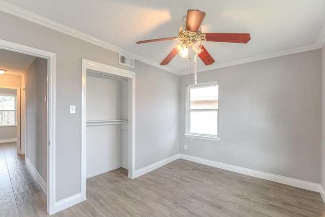 unfurnished bedroom featuring light wood-style flooring, multiple windows, visible vents, and ornamental molding