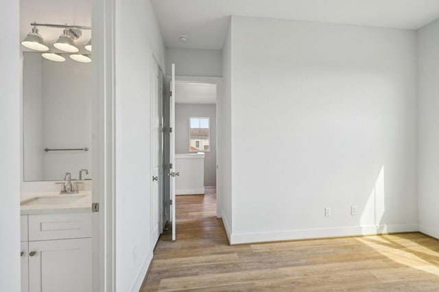 26726 Estuary Dr, Galveston, TX 77554 - hallway featuring light wood finished floors, a sink, and baseboards