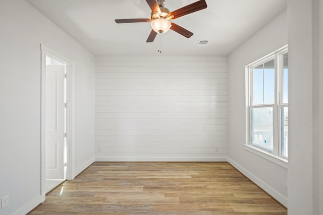 26726 Estuary Dr, Galveston, TX 77554 - empty room with ceiling fan, light wood-style flooring, wood walls, visible vents, and baseboards