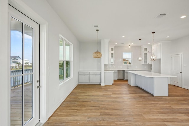 26726 Estuary Dr, Galveston, TX 77554 - kitchen with glass insert cabinets, white cabinets, light countertops, and decorative light fixtures