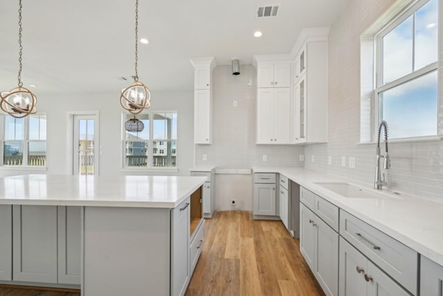 26726 Estuary Dr, Galveston, TX 77554 - kitchen with gray cabinetry, a kitchen island, a sink, hanging light fixtures, and backsplash