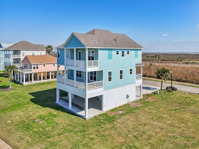 26726 Estuary Dr, Galveston, TX 77554 - back of house featuring a patio, a balcony, a yard, roof with shingles, and board and batten siding