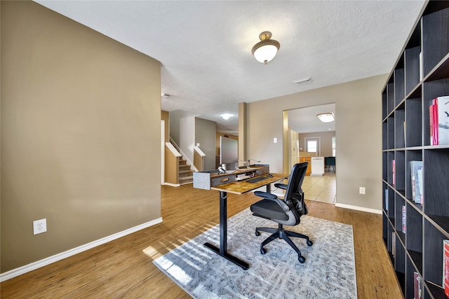 home office with visible vents, a textured ceiling, baseboards, and wood finished floors