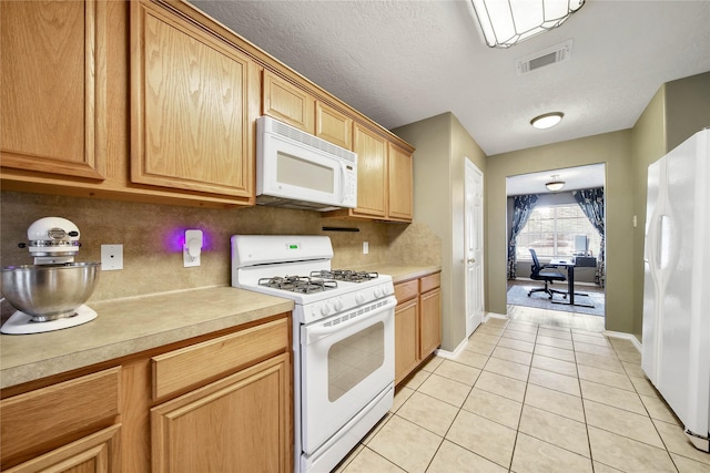 kitchen with light countertops, visible vents, decorative backsplash, light tile patterned flooring, and white appliances