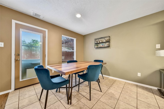 dining space with baseboards, visible vents, a textured ceiling, and light tile patterned flooring