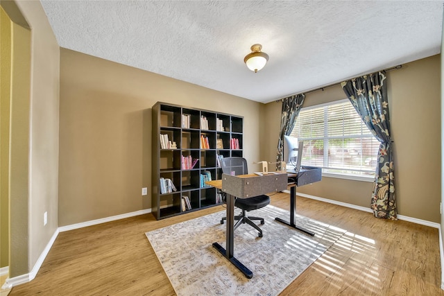 home office featuring a textured ceiling, baseboards, and wood finished floors