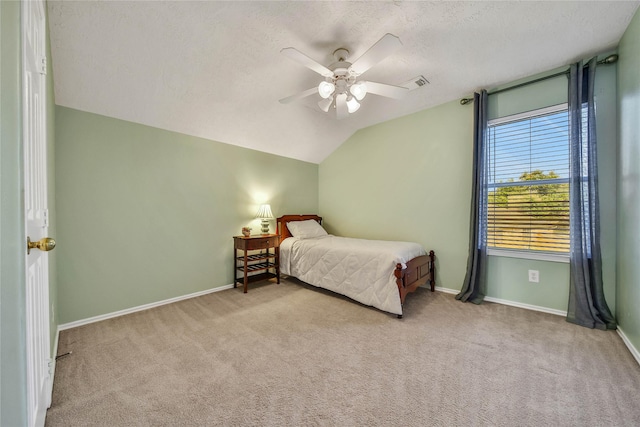 bedroom with baseboards, visible vents, light colored carpet, vaulted ceiling, and a textured ceiling