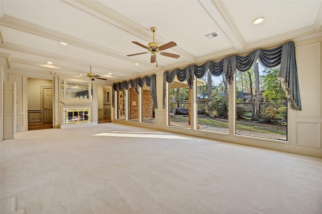 unfurnished living room featuring carpet floors, beam ceiling, a decorative wall, ornamental molding, and a glass covered fireplace