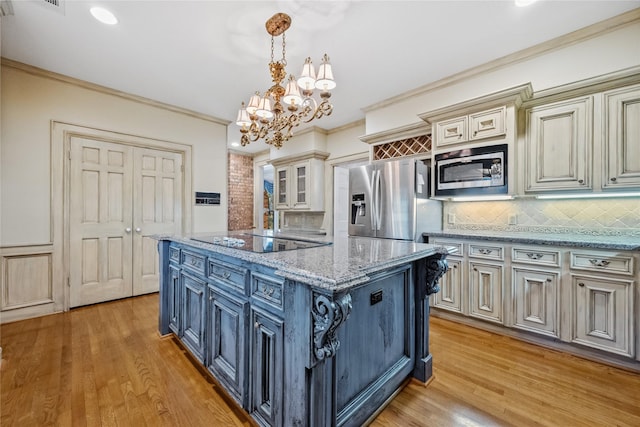 kitchen featuring appliances with stainless steel finishes, crown molding, light wood finished floors, and cream cabinets