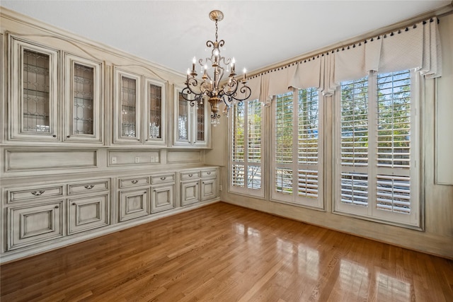 unfurnished dining area with light wood-type flooring, an inviting chandelier, and a wealth of natural light