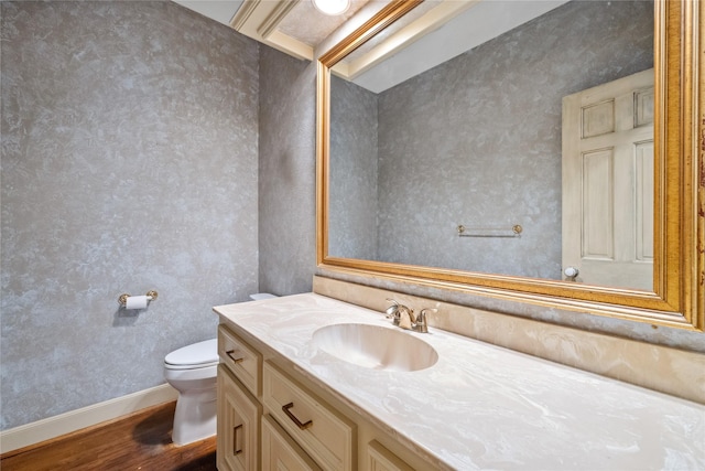 bathroom with toilet, baseboards, wood finished floors, and vanity