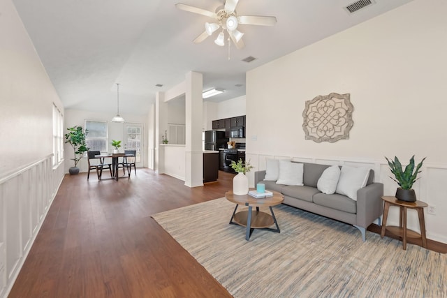 living room with lofted ceiling, dark wood-style flooring, wainscoting, and visible vents