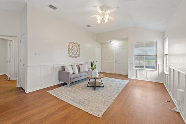 living room with lofted ceiling, wainscoting, visible vents, and wood finished floors