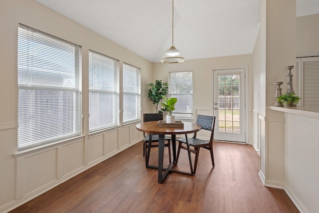 dining area featuring lofted ceiling, dark wood-style floors, and a decorative wall