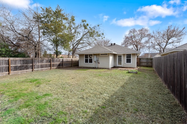 rear view of house with a fenced backyard and a yard