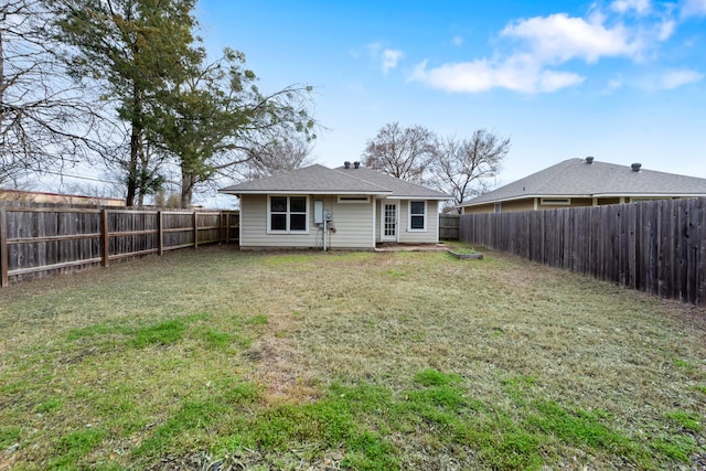 rear view of house with a lawn and a fenced backyard