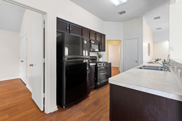 kitchen featuring black appliances, wood finished floors, light countertops, and visible vents