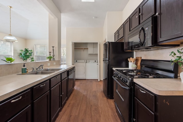 kitchen with light countertops, independent washer and dryer, a sink, and black appliances