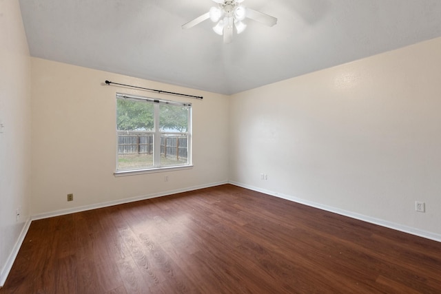 empty room featuring lofted ceiling, ceiling fan, dark wood finished floors, and baseboards