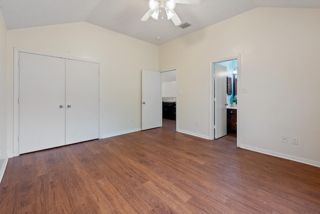 unfurnished bedroom featuring lofted ceiling, baseboards, visible vents, and dark wood finished floors