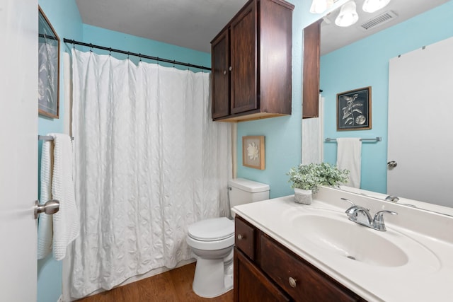 full bathroom featuring toilet, visible vents, wood finished floors, and vanity