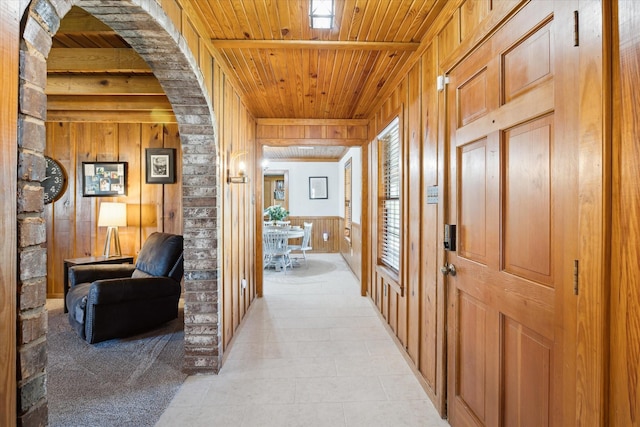 hall featuring wood walls, wood ceiling, and arched walkways