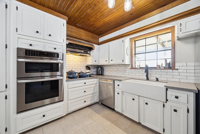 kitchen featuring tasteful backsplash, white cabinets, stainless steel appliances, light countertops, and a sink