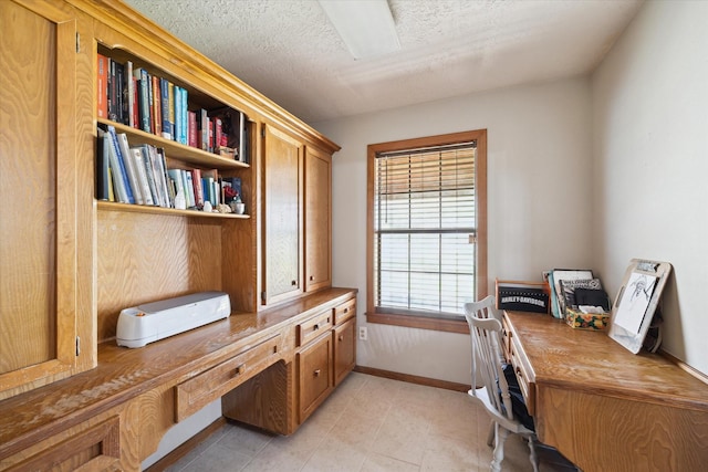 office area with light tile patterned flooring, a textured ceiling, and baseboards