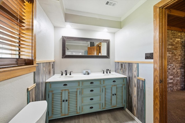 bathroom featuring double vanity, ornamental molding, a sink, and visible vents