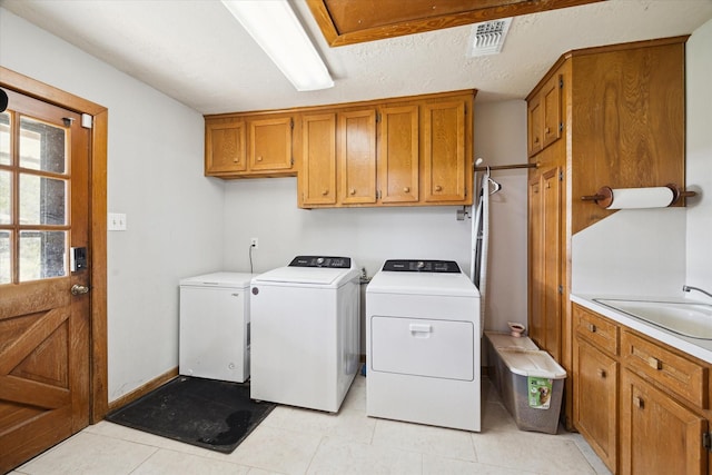 laundry area featuring cabinet space, light tile patterned floors, baseboards, washer and clothes dryer, and a sink