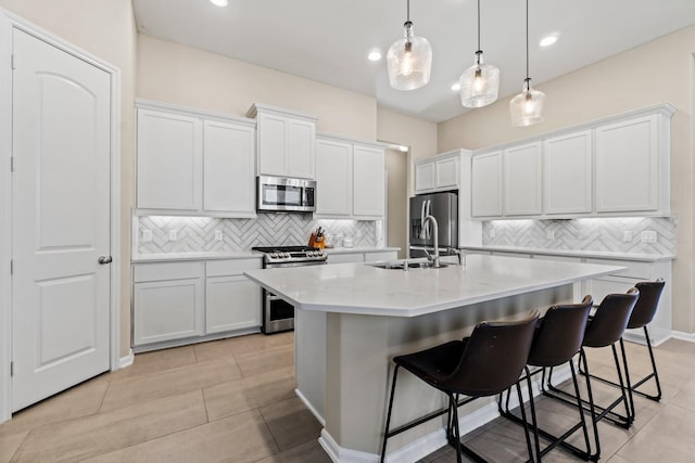 kitchen featuring white cabinets, a center island with sink, appliances with stainless steel finishes, and light countertops