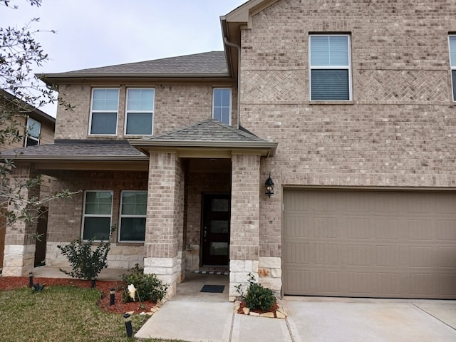 view of front of house featuring an attached garage, a shingled roof, concrete driveway, and brick siding