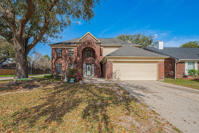 traditional home with driveway, a shingled roof, a front yard, an attached garage, and brick siding