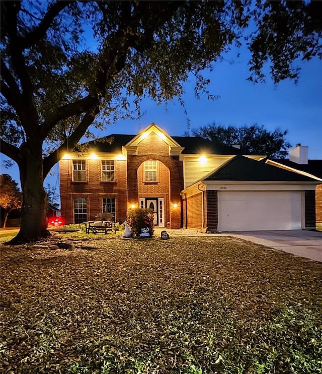 traditional-style house with brick siding, an attached garage, and driveway