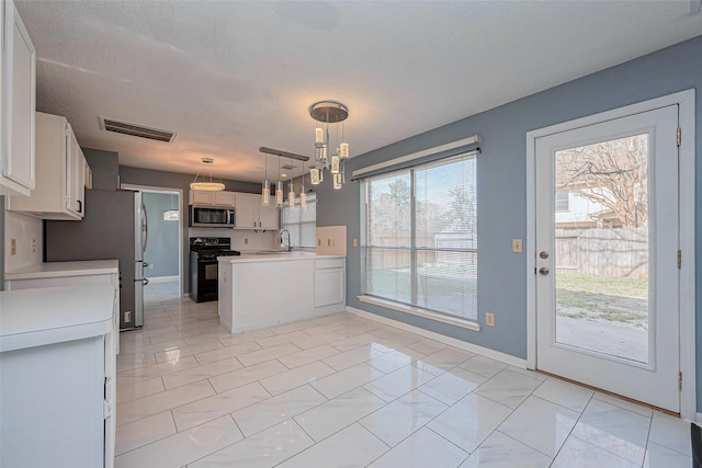 kitchen featuring visible vents, a sink, stainless steel appliances, light countertops, and a chandelier