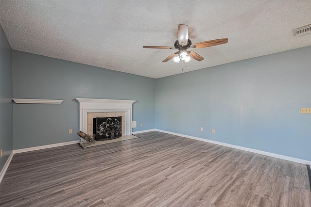 unfurnished living room featuring visible vents, baseboards, ceiling fan, a fireplace, and wood finished floors