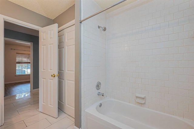 bathroom featuring baseboards, a textured ceiling, washtub / shower combination, and tile patterned flooring