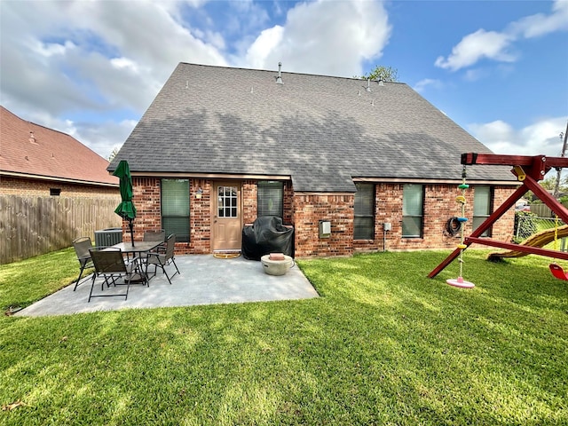 back of property featuring a shingled roof, fence, a yard, a patio area, and brick siding