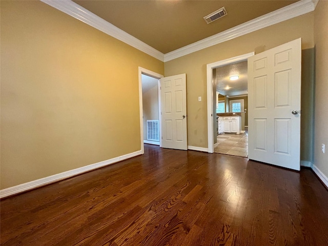 unfurnished bedroom featuring baseboards, visible vents, wood finished floors, and ornamental molding