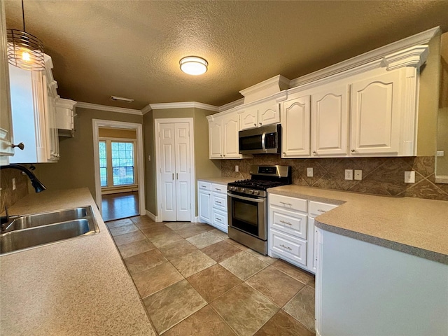 kitchen featuring a sink, appliances with stainless steel finishes, white cabinets, and light countertops