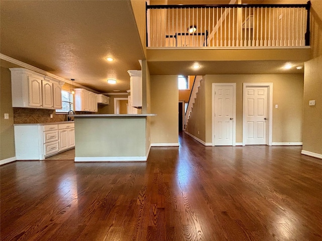 kitchen featuring open floor plan, white cabinetry, baseboards, and dark wood-style flooring