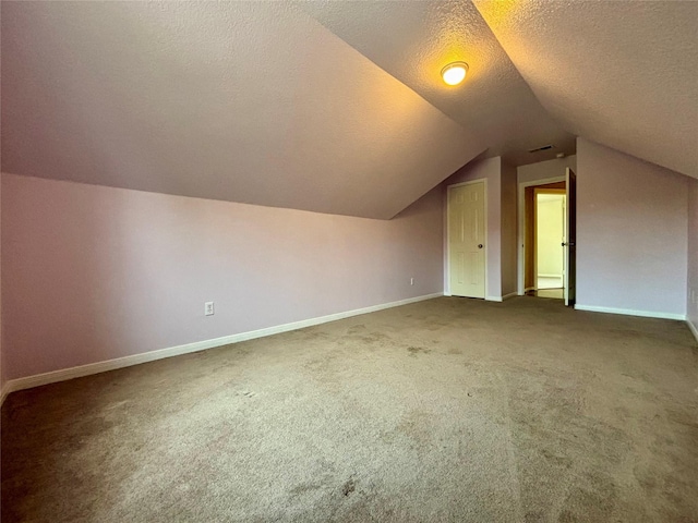 bonus room with a textured ceiling, vaulted ceiling, dark carpet, and baseboards